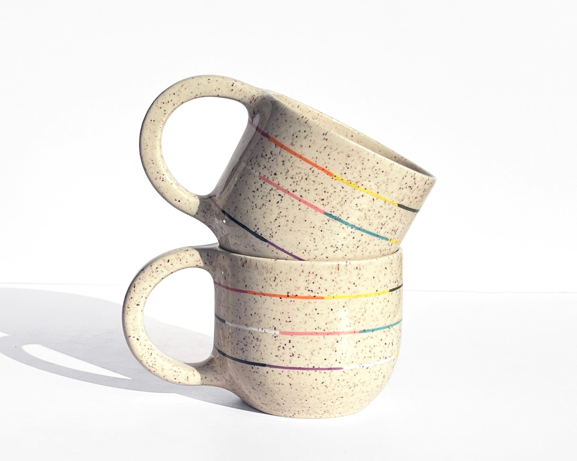 Collection of cups and pots with colorful thin stripes in celebration of pride, joy, identity and representation.