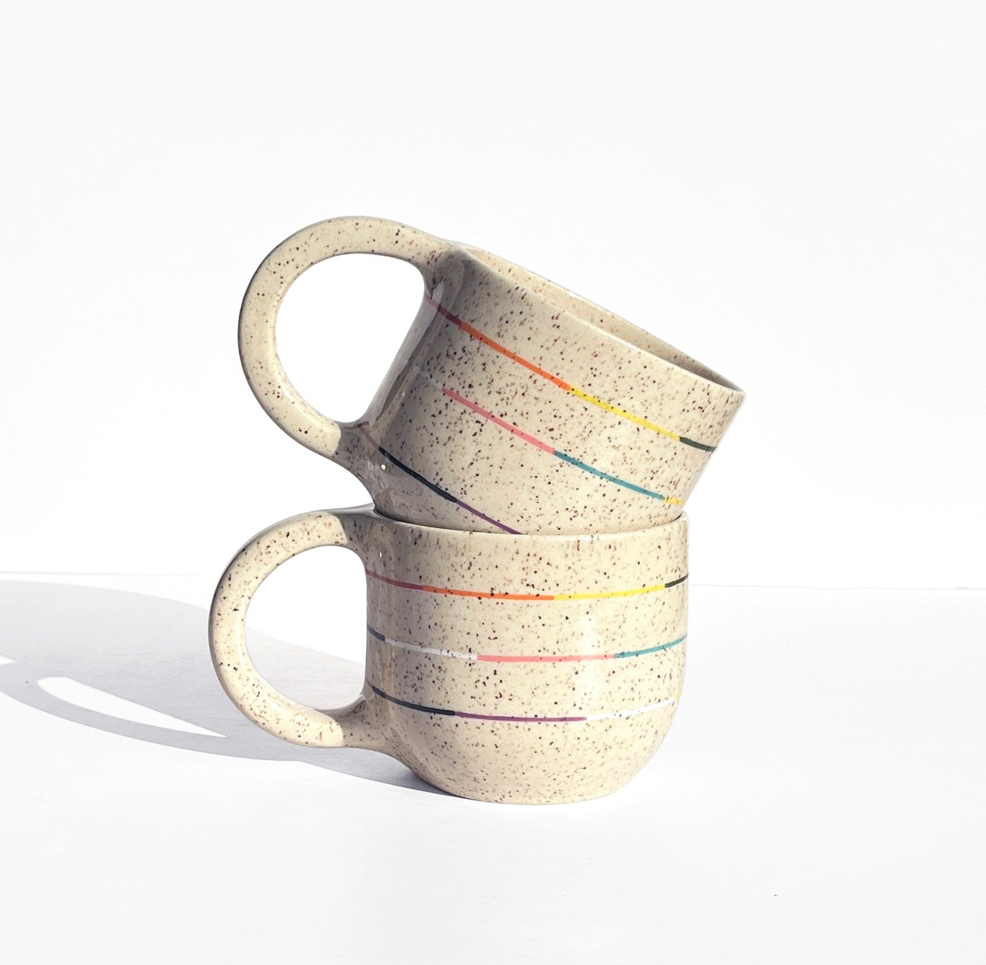 Collection of cups and pots with colorful thin stripes in celebration of pride, joy, identity and representation.